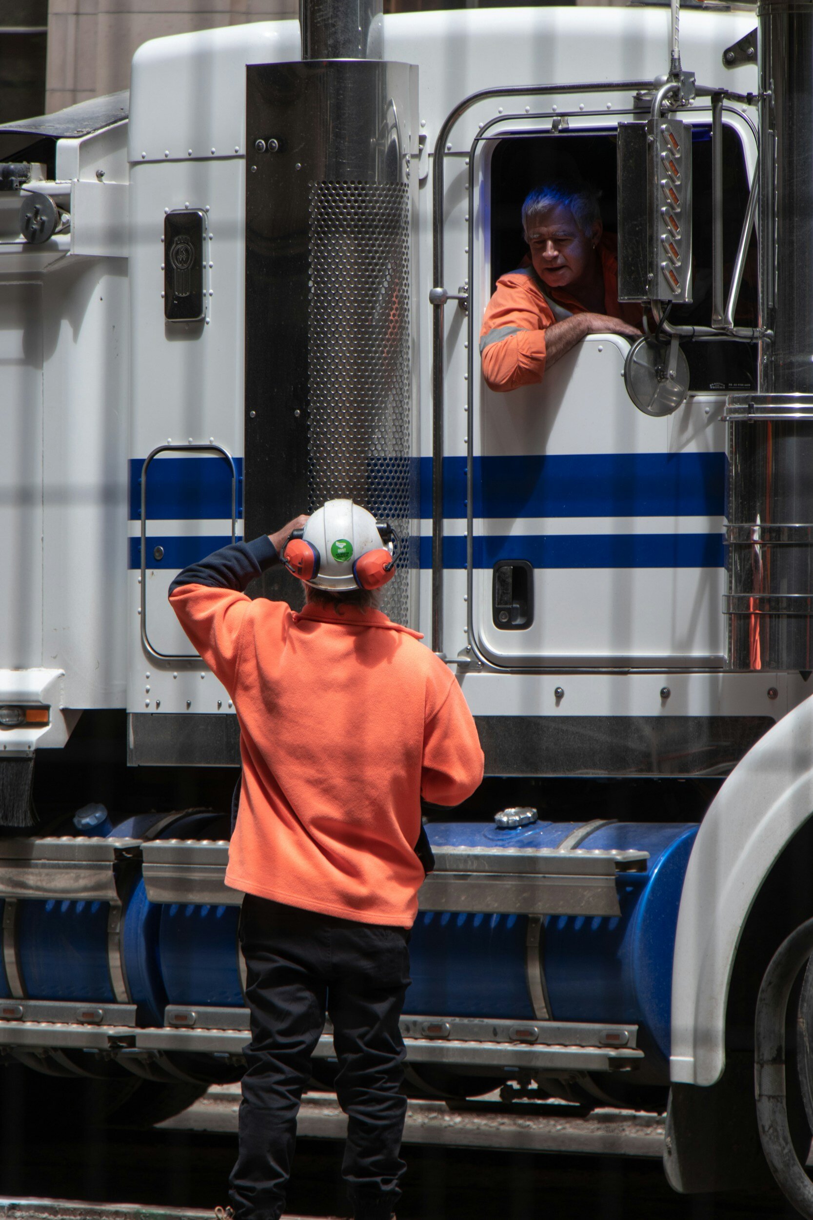 Two Truck Drivers conversing inside and outside a Semi Truck Two Truck Drivers conversing inside and outside a Semi Truck