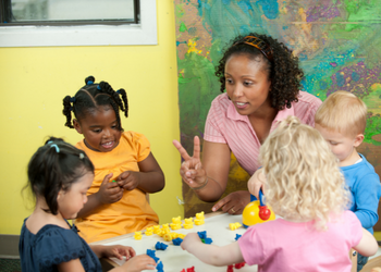 Female daycare worker attending to a group of toddlers playing